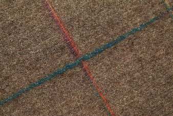 Close-up of brown wool fabric with colorful woven threads