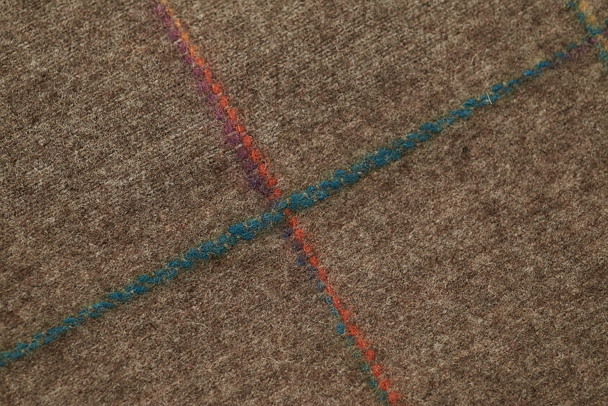 Close-up of brown wool fabric with colorful woven threads