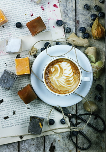 Flat lay of latte art coffee with sweets and book