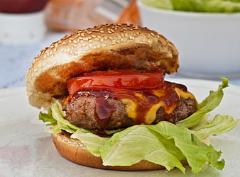 Close-up of a grilled cheeseburger with tomato, lettuce, and BBQ sauce