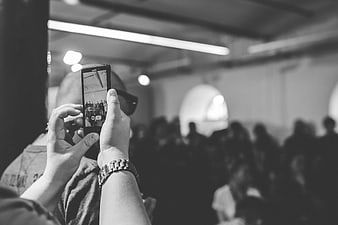 Black and white photo of hands holding smartphone at event