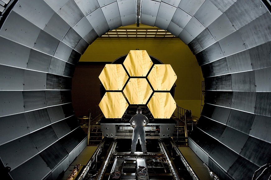 Astronomer Standing Before Space Telescope Mirror Assembly in Cleanroom