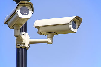 Dual CCTV Security Cameras on Pole Against Blue Sky