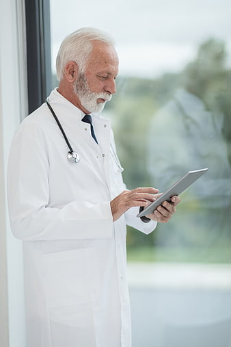 Senior Doctor Using Tablet by Window