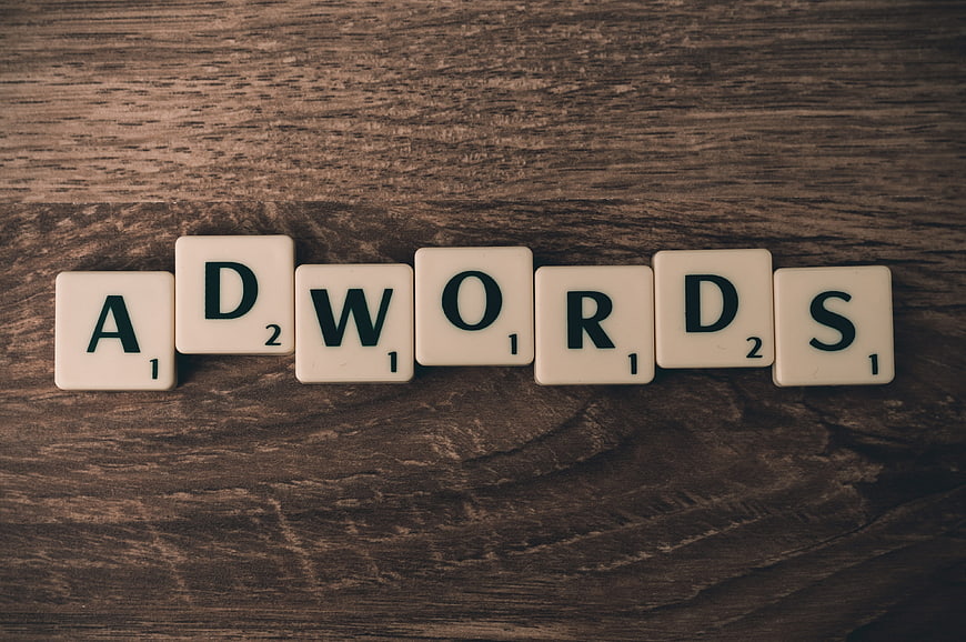 Scrabble Tiles Spelling Adwords on Wooden Background