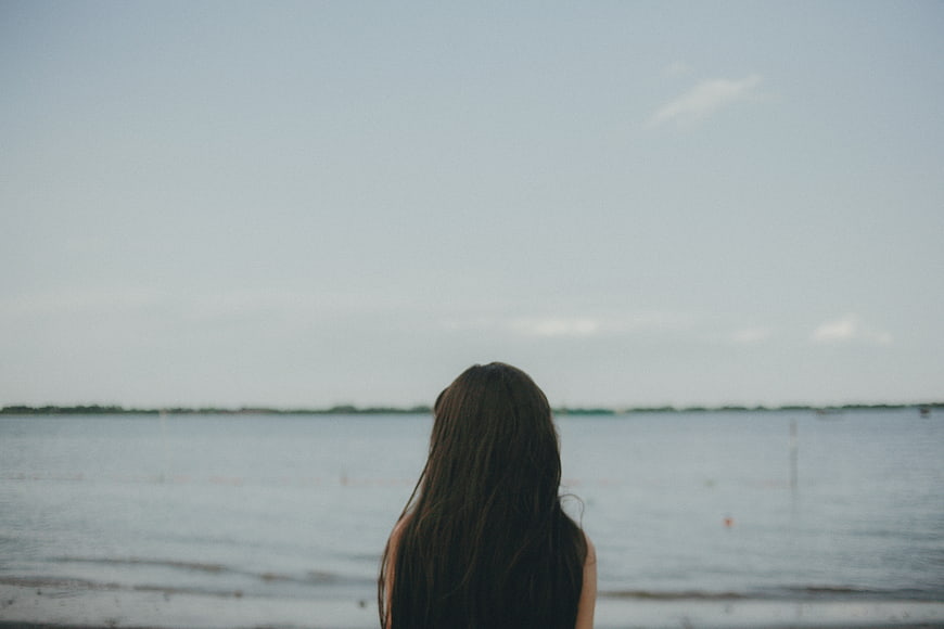 Woman with long hair looking out at the ocean horizon