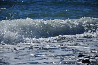 Crashing ocean wave with white foam on sunny day