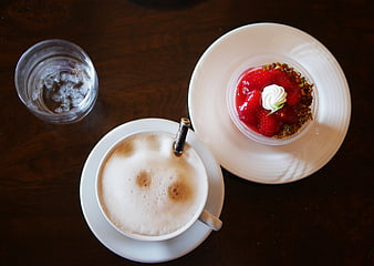 Overhead view of cappuccino and strawberry dessert on wooden table