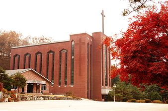 Red brick church with cross in autumn landscape