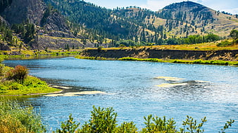 Scenic river flowing through mountain valley with green hills
