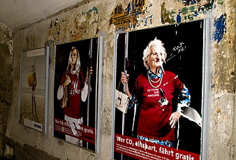 Torn posters on gritty urban wall with elderly woman