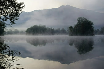 Misty lake landscape with mountain reflections and fog