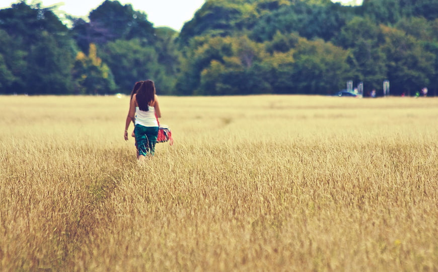 Woman walking away through golden wheat field