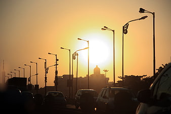 Silhouette of street lamps and cars against golden sunset
