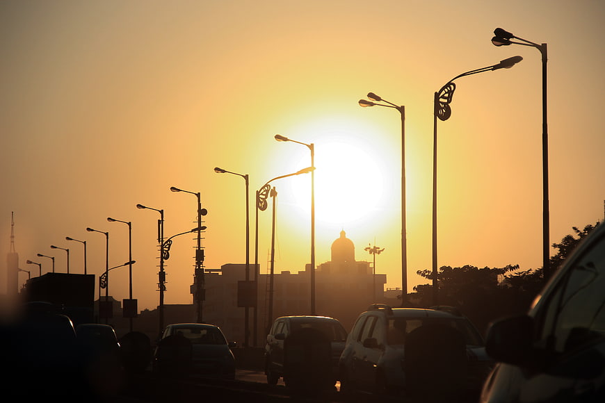 Silhouette of street lamps and cars against golden sunset