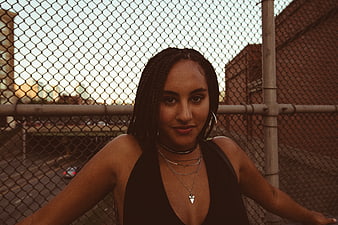 Stylish Woman with Braids Leaning on Chainlink Fence