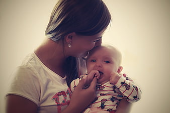 Mother kissing baby on the forehead in a warm indoor portrait