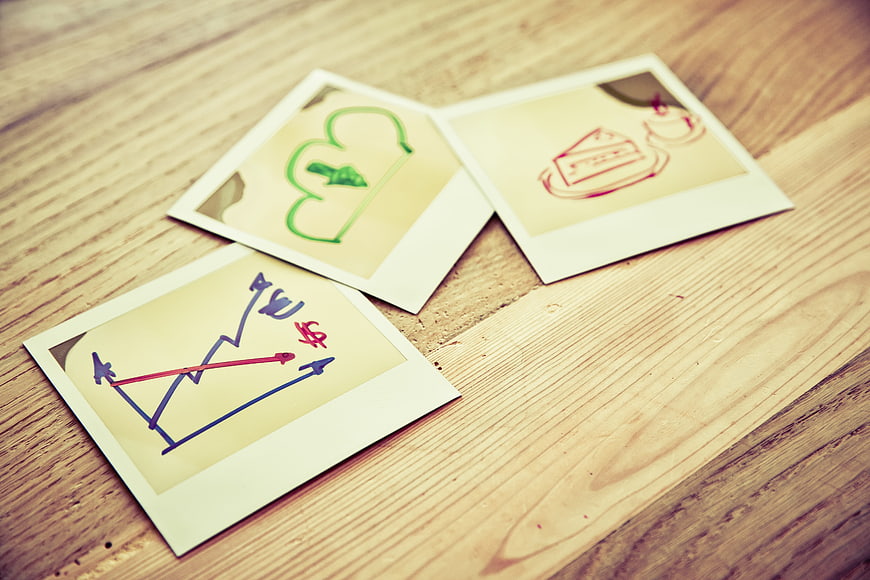 Hand-drawn financial charts and symbols on vintage polaroid photos