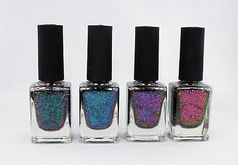 Four bottles of colorful glitter nail polish on white background