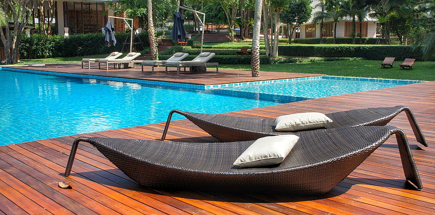 Luxury Resort Swimming Pool With Wicker Loungers And Tropical Garden