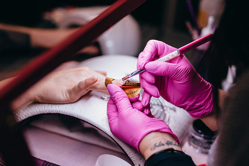 Close-up of nail technician applying gel polish with brush