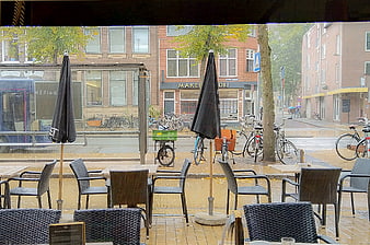 Empty cafe terrace on rainy street with bicycles and tram