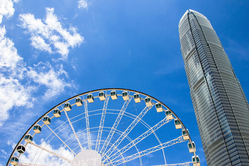 Low angle view of a Ferris wheel and skyscraper against a blue sky