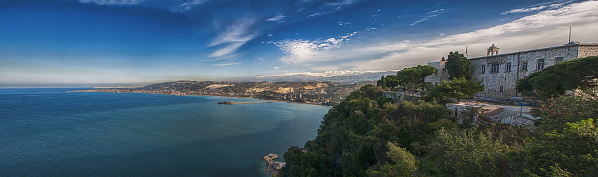 Panoramic coastal landscape with historic stone building and blue sea