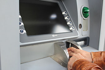 Close-up of hands withdrawing cash from an ATM machine