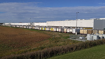 Logistics warehouse with parked trailers and autumn field