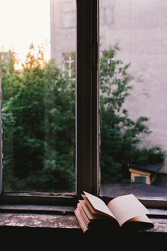 Open book on windowsill with blurred city view