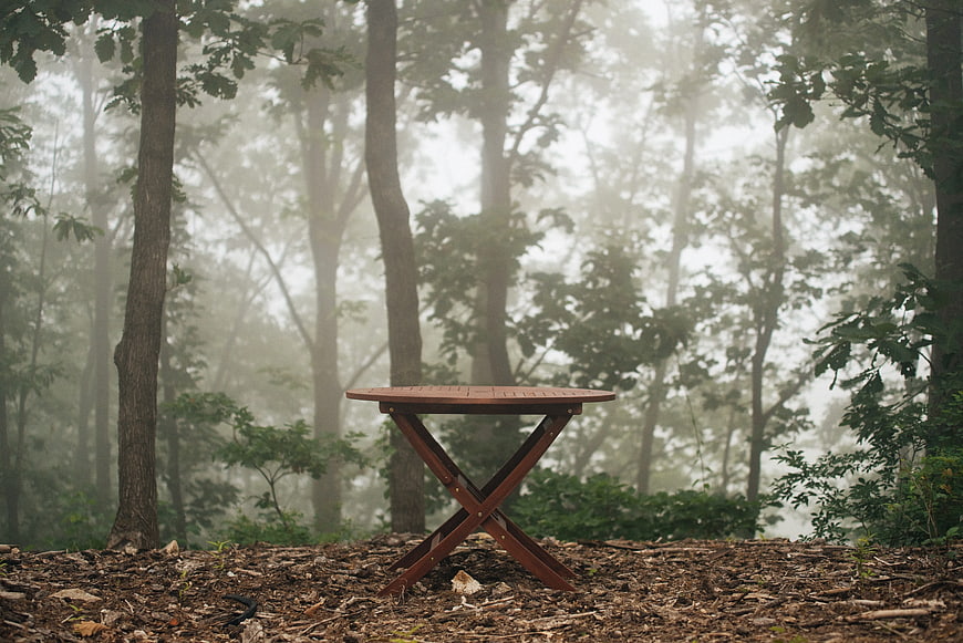 Lone wooden table in misty forest clearing
