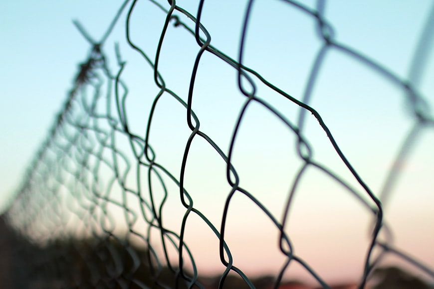 Close-up of chain-link fence against soft sunset sky