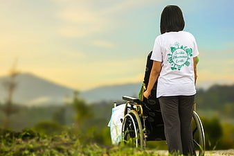 Woman pushing wheelchair in nature with environmental logo