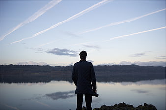 Man with Camera Standing by Lake at Dusk