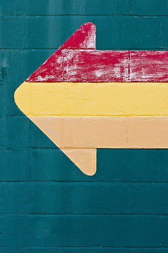 Colorful painted arrow on teal brick wall