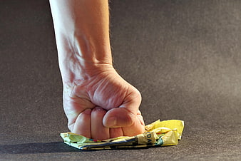 Hand Crushing Crumpled Paper on Dark Surface