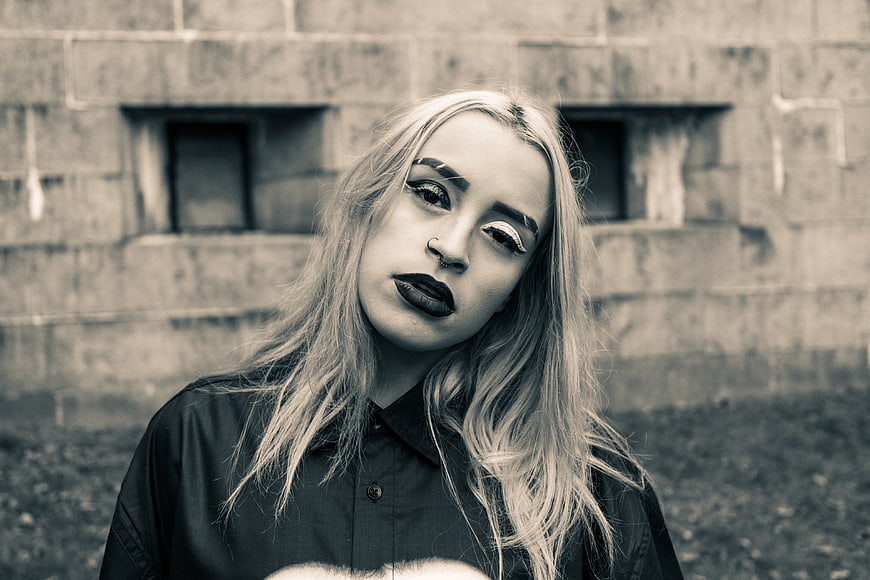 Gothic woman with dramatic makeup against concrete wall