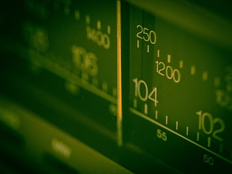 Close-up of green radio frequency dial with numbers 102, 104, 1200