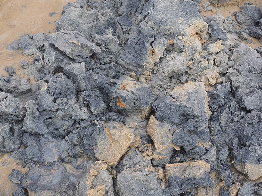 Close-up of wet gray mud and sand texture on beach