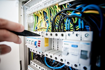Electrician repairing circuit breaker panel with screwdriver