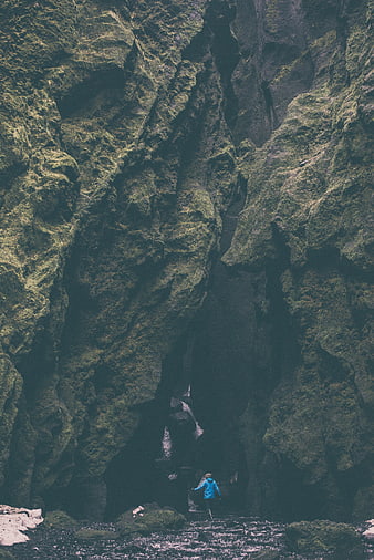 Woman in Blue Jacket Exploring Mossy Rock Cave