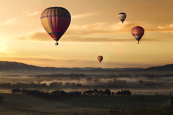 Hot Air Balloons Flying Over Misty Valley at Sunrise