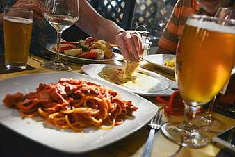 Friends enjoying Italian pasta and beer at a restaurant table