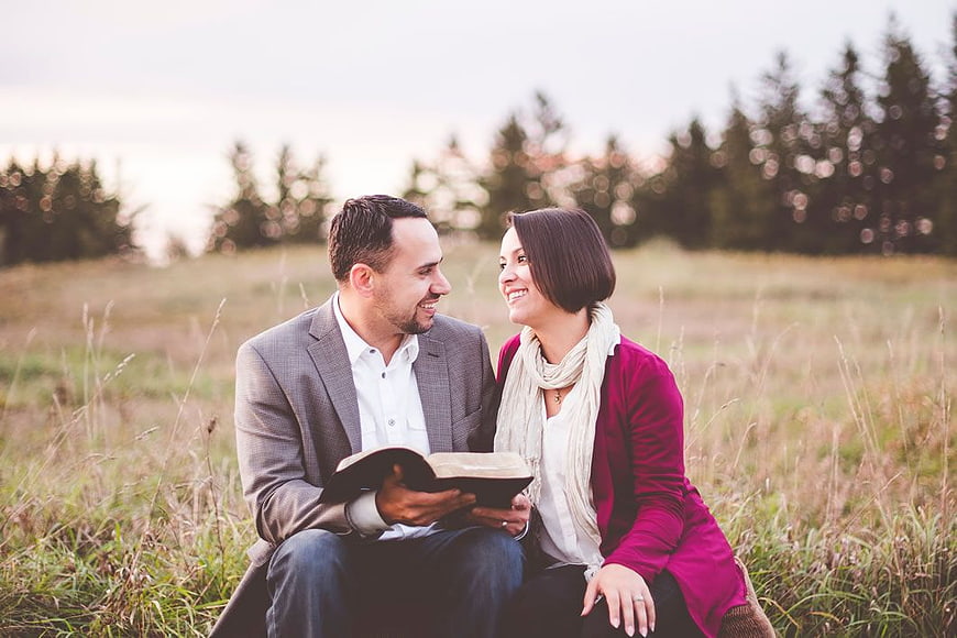 Happy couple reading a book together in a grassy field