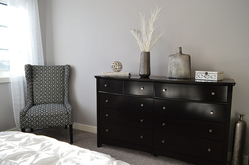 Modern Bedroom Interior with Black Dresser and Patterned Chair