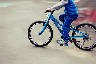 Child Riding Blue Bicycle in Motion