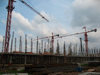 Construction site with multiple cranes and steel rebar columns