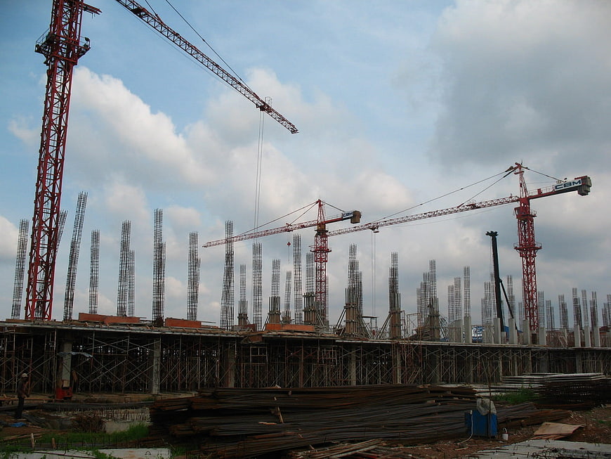 Construction site with multiple cranes and steel rebar columns