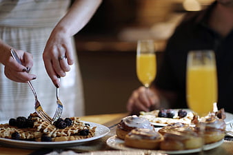 Couple Eating Waffles and Cinnamon Rolls with Orange Juice